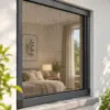 Plissee-Insektenschutz in Anthrazit an einem Fenster – Blick ins Schlafzimmer
